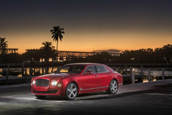 Elegancki czerwony Bentley na tle palm